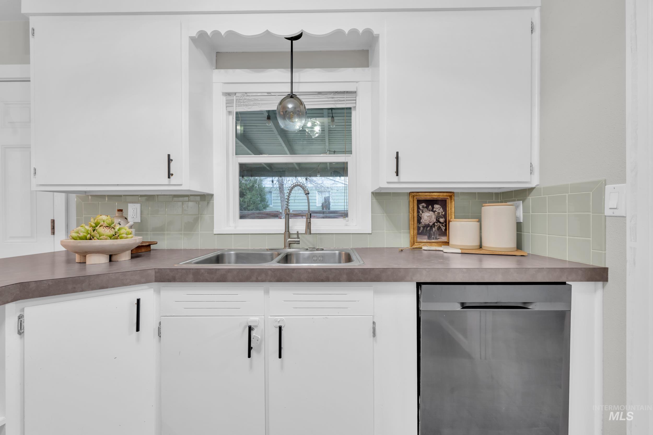 2908 Meadowbrook Drive Boise, ID 83705 - Photo 14 of 29 Kitchen featuring white cabinets, dishwasher, backsplash, pendant lighting, and dark countertops