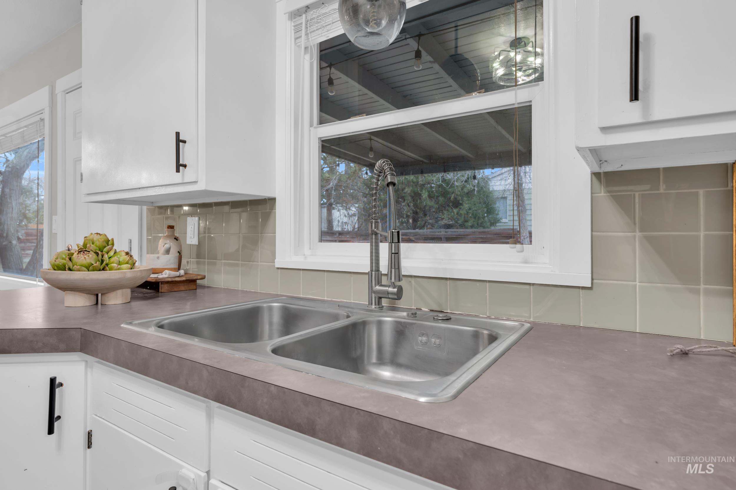 2908 Meadowbrook Drive Boise, ID 83705 - Photo 15 of 29 Kitchen featuring white cabinets, backsplash, and healthy amount of natural light