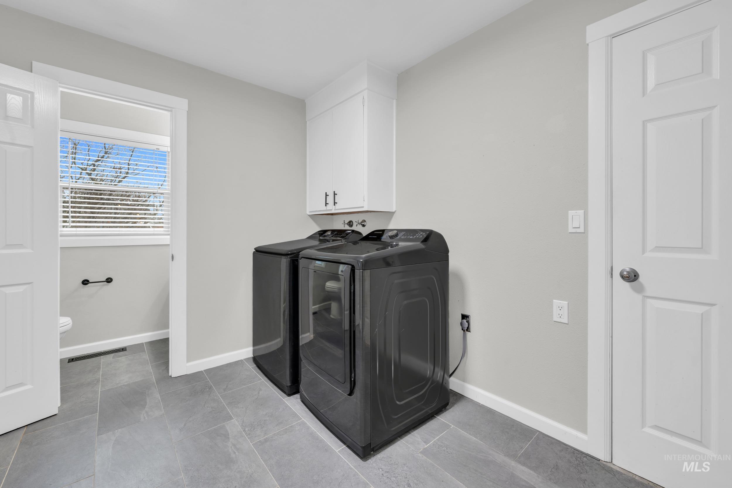 2908 Meadowbrook Drive Boise, ID 83705 - Photo 24 of 29 Washroom featuring cabinet space, washing machine and clothes dryer, and light tile patterned flooring