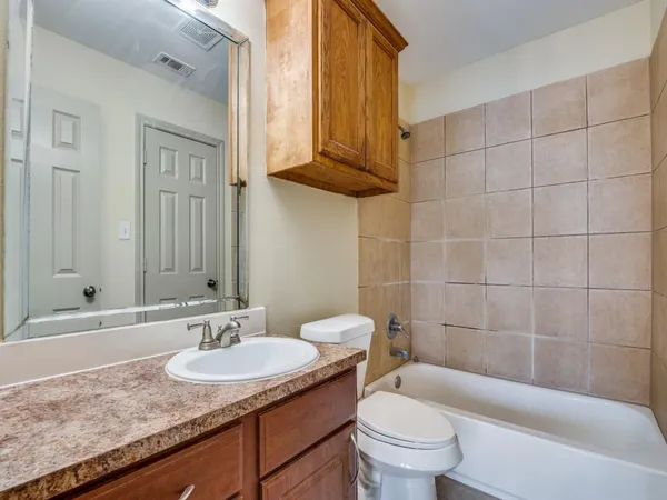 a bathroom with a granite countertop sink a toilet a mirror and shower