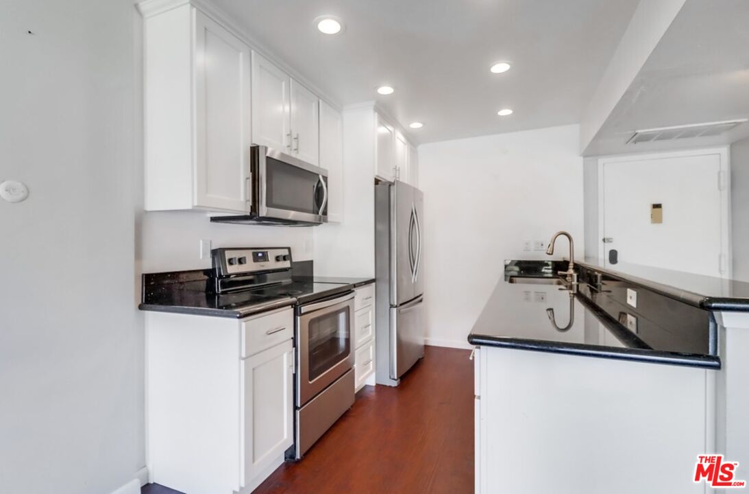 a kitchen with granite countertop a sink stove and refrigerator