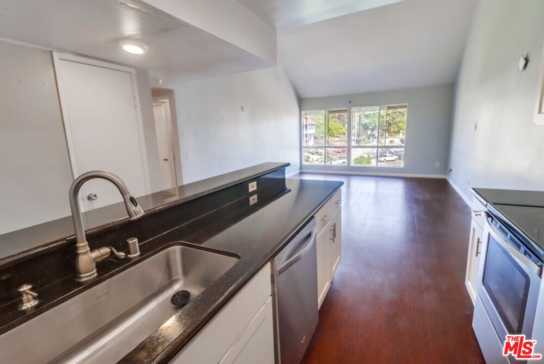 6171 Rancho Mission Road, Unit 317 San Diego, CA 92108 - Photo 6 of 26 a kitchen with kitchen island a sink wooden floor and a large window