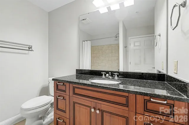 a bathroom with a granite countertop sink a toilet and a mirror