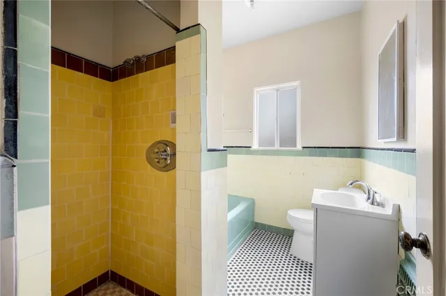 a bathroom with a sink a toilet a shower and a window