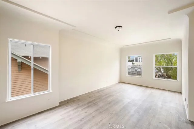 a view of an empty room with a window and wooden floor