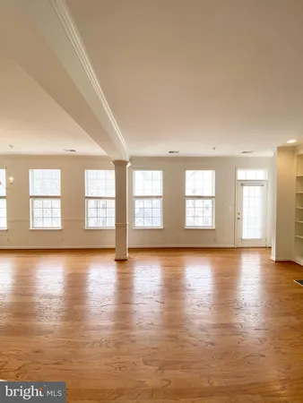an empty room with wooden floor fireplace and windows
