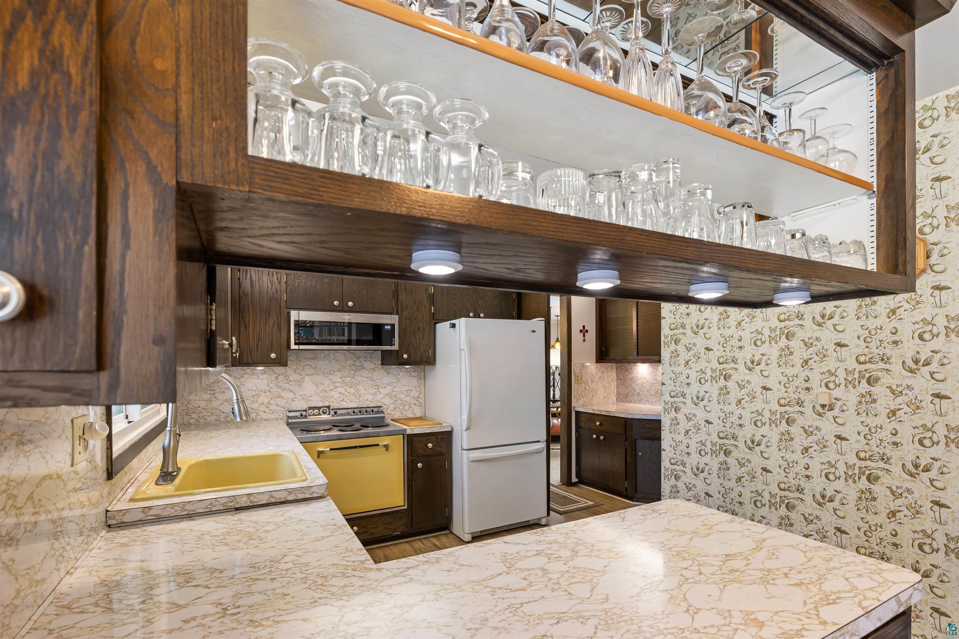 3975 Long Lake Shores Road Eveleth, MN 55734 - Photo 16 of 79 Kitchen featuring dark wood finish cabinetry, light countertops, freestanding refrigerator, and stainless steel microwave