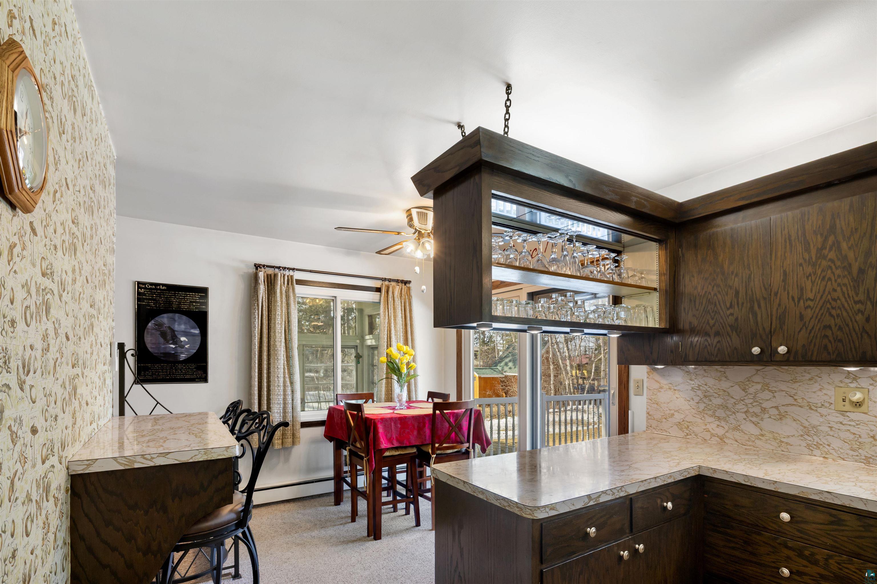 3975 Long Lake Shores Road Eveleth, MN 55734 - Photo 17 of 79 Kitchen featuring dark wood finish cabinets, a peninsula, backsplash, a ceiling fan, and a baseboard heating unit