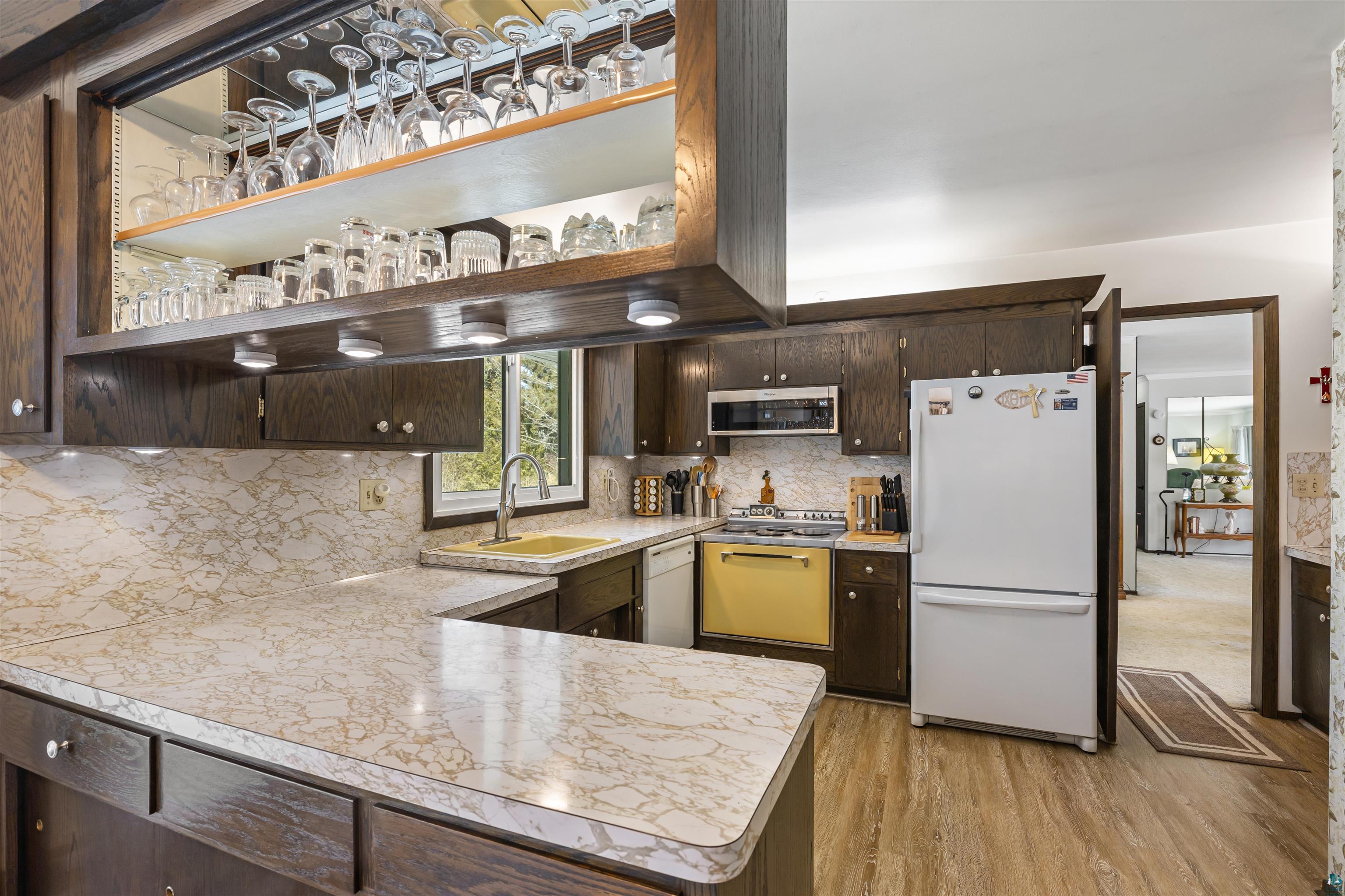 3975 Long Lake Shores Road Eveleth, MN 55734 - Photo 18 of 79 Kitchen with dark wood finish cabinetry, white appliances, a peninsula, light wood-style flooring, and light countertops