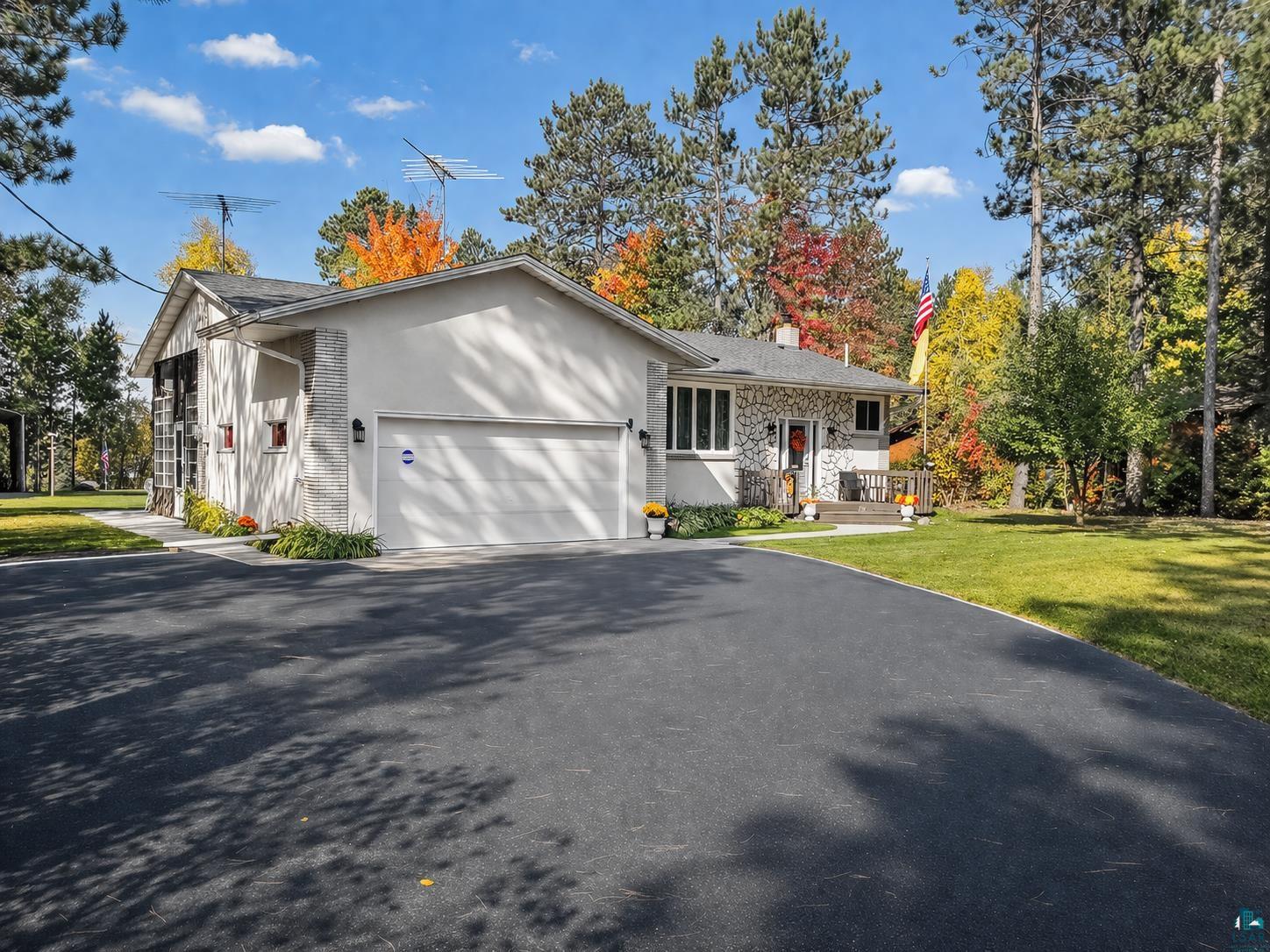3975 Long Lake Shores Road Eveleth, MN 55734 - Photo 3 of 79 View of front facade with an attached garage, asphalt driveway, a chimney, a front yard, and stone siding