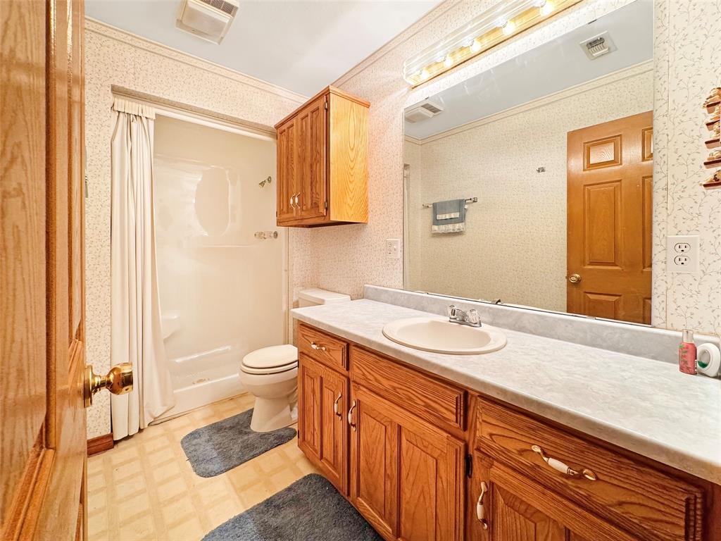 3870 County Road Arthur City, TX 75411 - Photo 18 of 39 Bathroom featuring a single vanity with an integrated sink, a large wall-mounted mirror, and a shower with a privacy curtain
