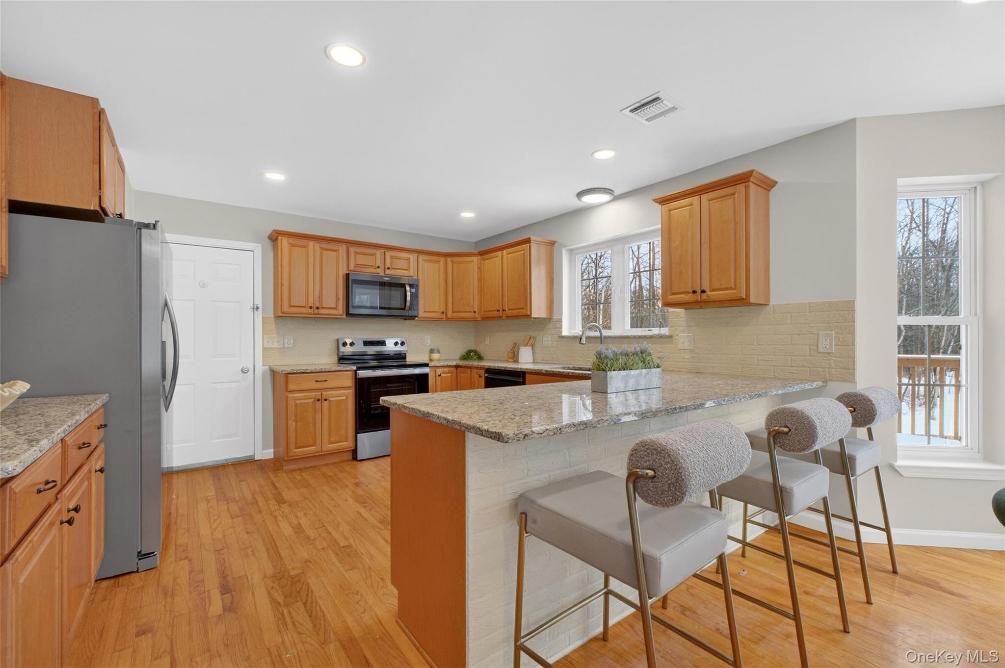 33 Berea Road Walden, NY 12586 - Photo 18 of 44 Kitchen with a kitchen bar, stainless steel appliances, light stone countertops, light wood finished floors, and decorative backsplash