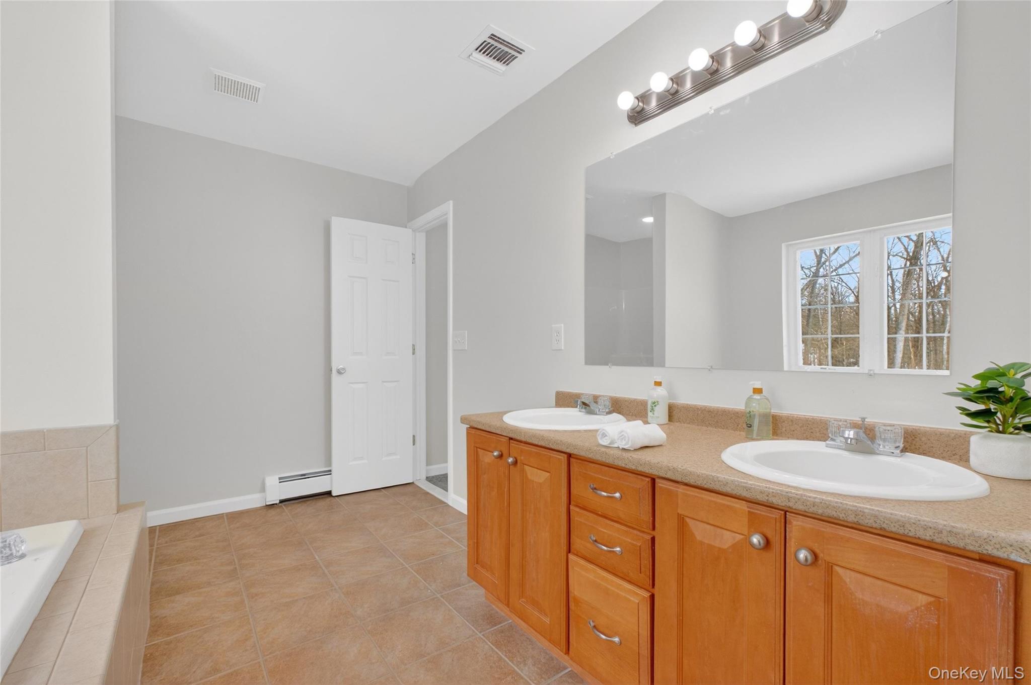 33 Berea Road Walden, NY 12586 - Photo 27 of 44 Full bathroom with double vanity, light tile patterned floors, tiled tub, and baseboard heating
