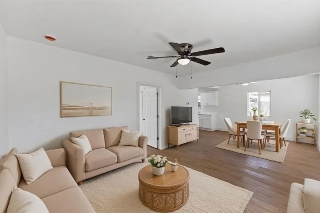 an empty room with wooden floor chandelier fan and windows