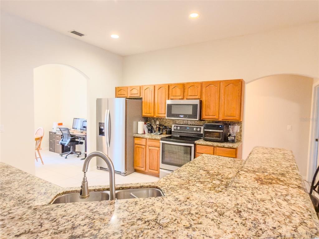 4 Weston Road Leesburg, FL 34748 - Photo 14 of 55 a kitchen with stainless steel appliances kitchen island granite countertop a stove a sink and a microwave