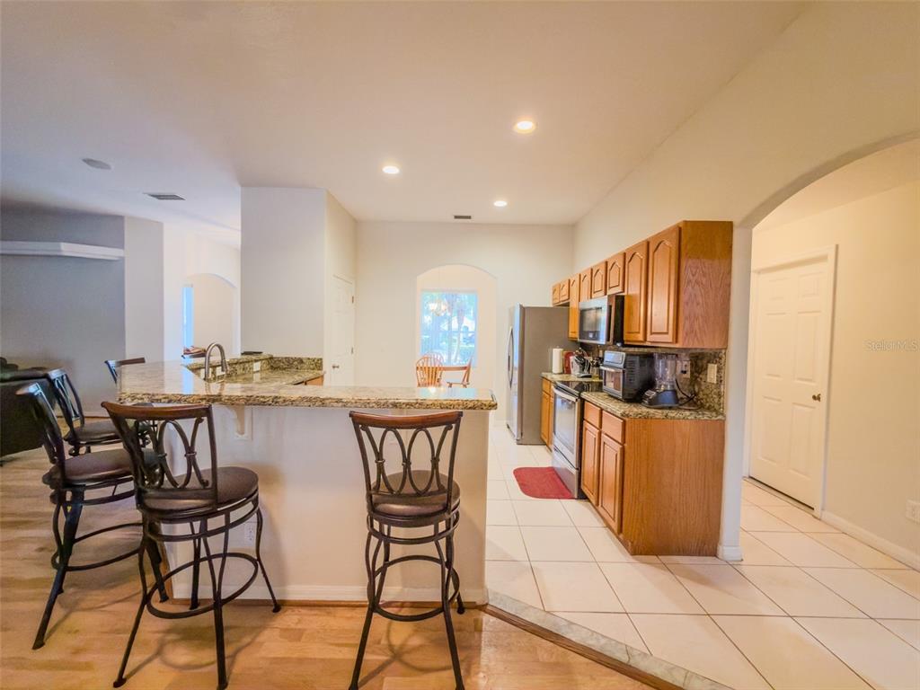 4 Weston Road Leesburg, FL 34748 - Photo 16 of 55 a kitchen with stainless steel appliances kitchen island granite countertop a table chairs and a refrigerator