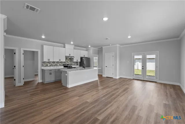 a large kitchen with stainless steel appliances granite countertop a large counter top a sink and a refrigerator