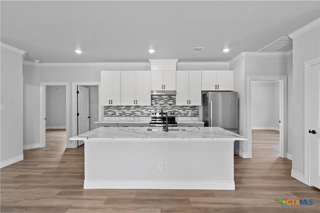 a view of a kitchen with kitchen island a refrigerator and a stove with wooden floor