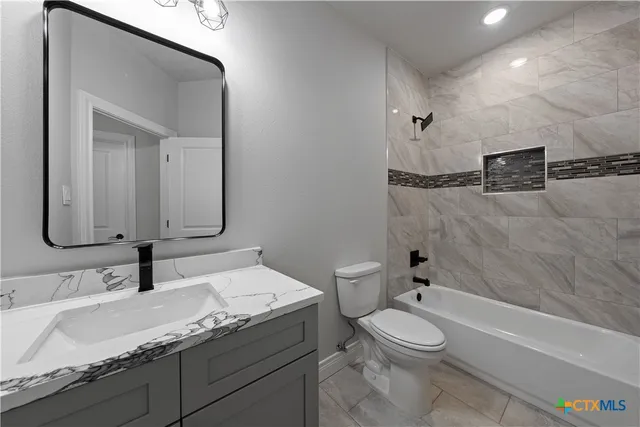 a bathroom with a granite countertop toilet sink and mirror