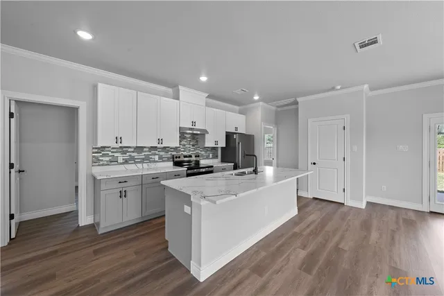 a kitchen with white cabinets appliances and wooden floor