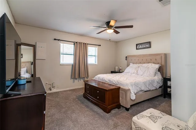 a bedroom with a bed and a flat tv screen on the dresser