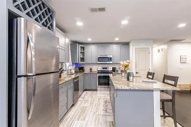 a kitchen with kitchen island granite countertop stainless steel appliances cabinets a sink and a refrigerator