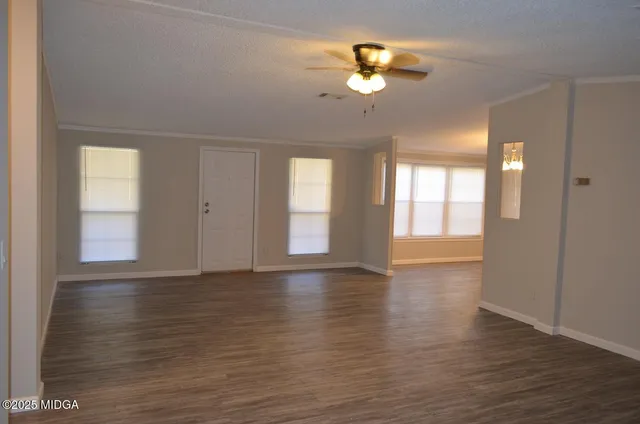 a view of an empty room with window and wooden floor