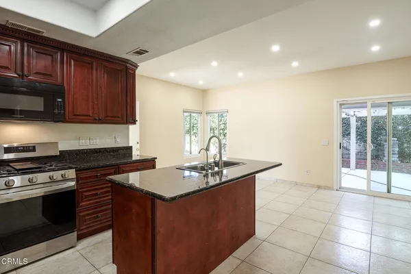 a kitchen with granite countertop a stove sink and cabinets