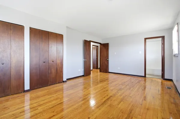 a view of an empty room with wooden floor and closet