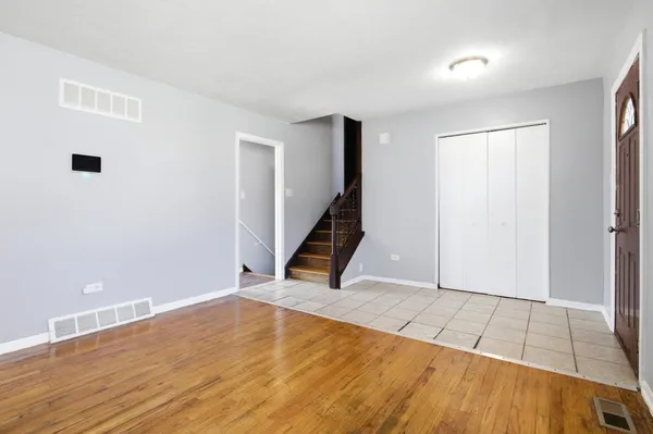 a view of an empty room with wooden floor and stairs