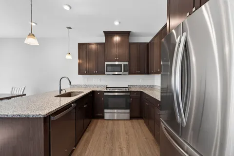 a kitchen with stainless steel appliances granite countertop a sink a stove a refrigerator and a sink