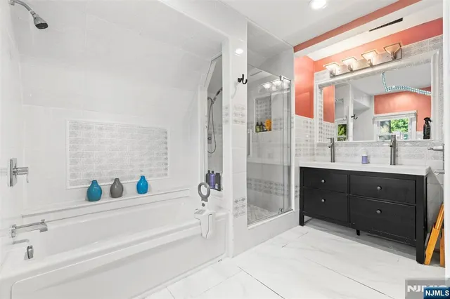 a bathroom with a tub sink shower and mirror