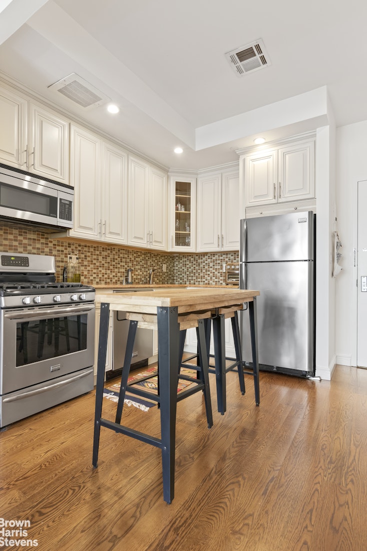199 Huron Street, Unit 4D Brooklyn, NY 11222 - Photo 4 of 8 a kitchen with kitchen island a stove a refrigerator and wooden floor