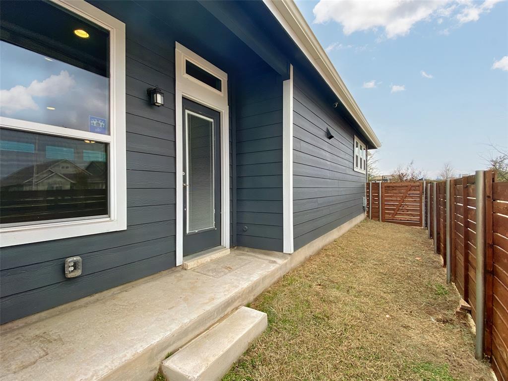 8901 Panhandle Drive Austin, TX 78747 - Photo 19 of 21 Exterior featuring horizontal siding, white trim windows, a glass-paneled door with transom, a concrete patio, and a wood privacy fence with gate