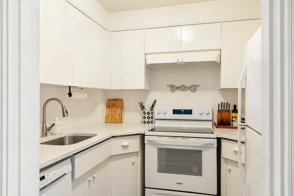 a kitchen with white cabinets and appliances