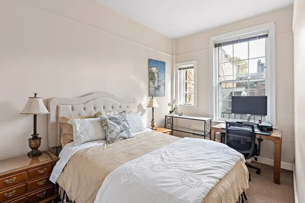 a bedroom with bed a flat tv screen and a dresser