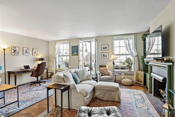 a living room with furniture a fireplace a flat screen tv and windows