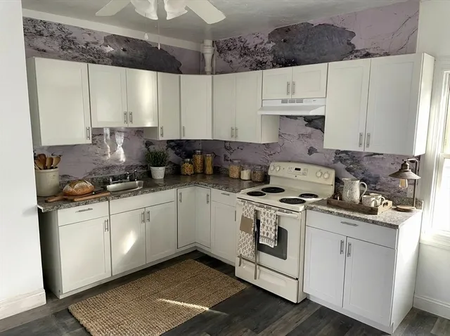 a kitchen with stainless steel appliances granite countertop a stove a sink and white cabinets