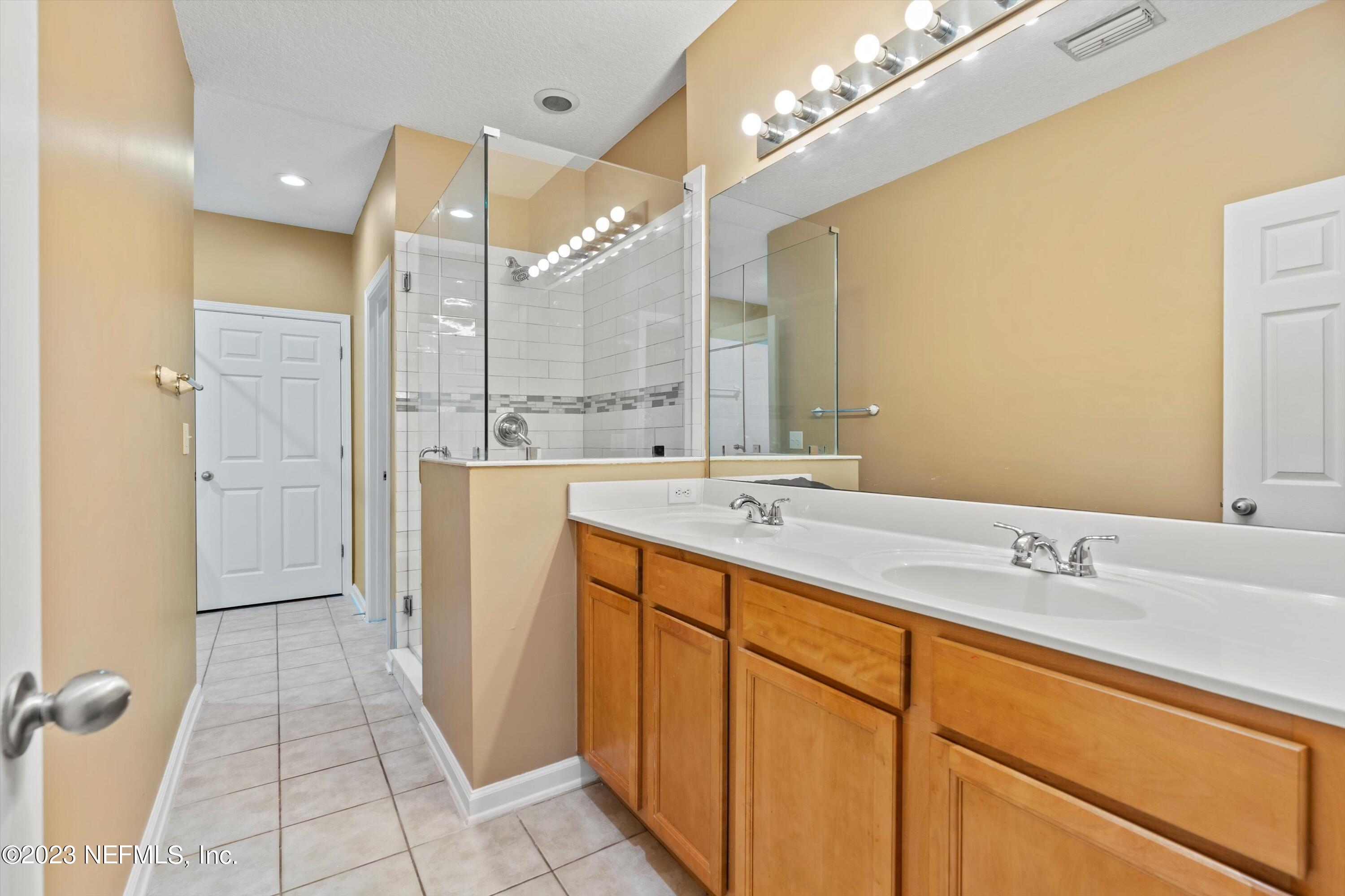 5663 Greenland Road, Unit 1005 Jacksonville, FL 32258 - Photo 22 of 30 a bathroom with a double vanity sink a mirror and a shower