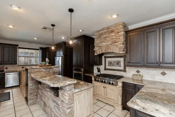 a kitchen with kitchen island granite countertop a stove and a sink