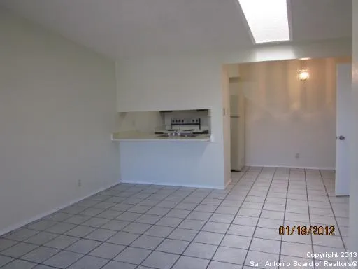 an empty room with kitchen space and window