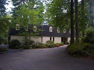 front view of house with a yard and trees all around