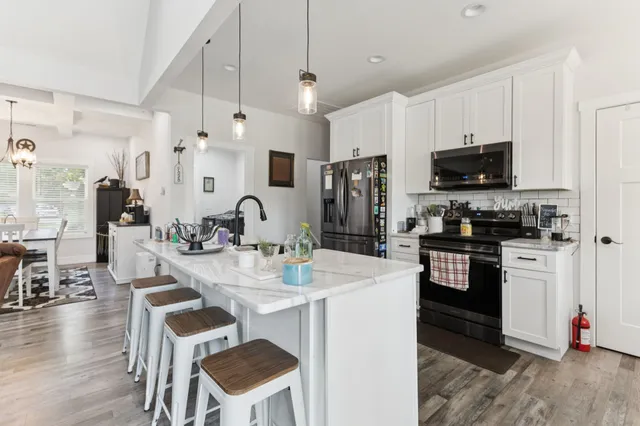 a kitchen with stainless steel appliances kitchen island granite countertop a stove a sink a refrigerator and a microwave