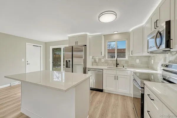 a kitchen with stainless steel appliances granite countertop a lot of counter space and wooden floors