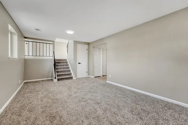 a view of an empty room with stairs and a window