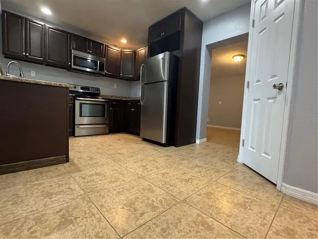 a kitchen with stainless steel appliances granite countertop a sink a stove and a refrigerator