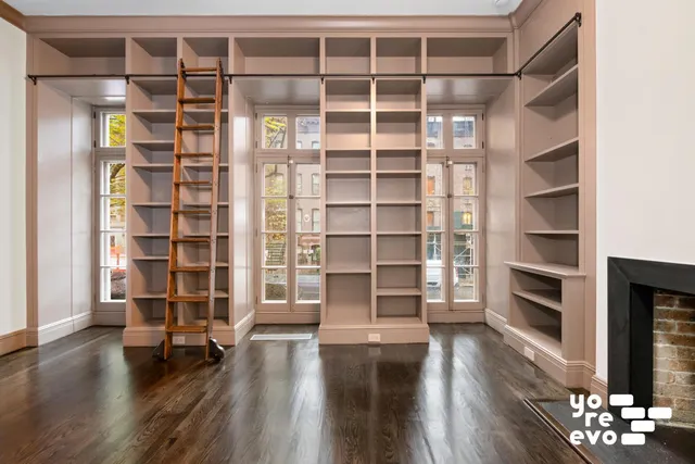 a view of an empty room with a fireplace and wooden floor