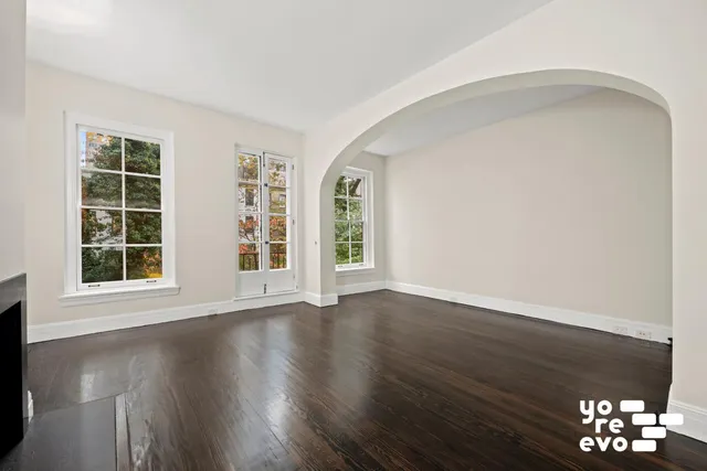 a view of an empty room with a window and wooden floor