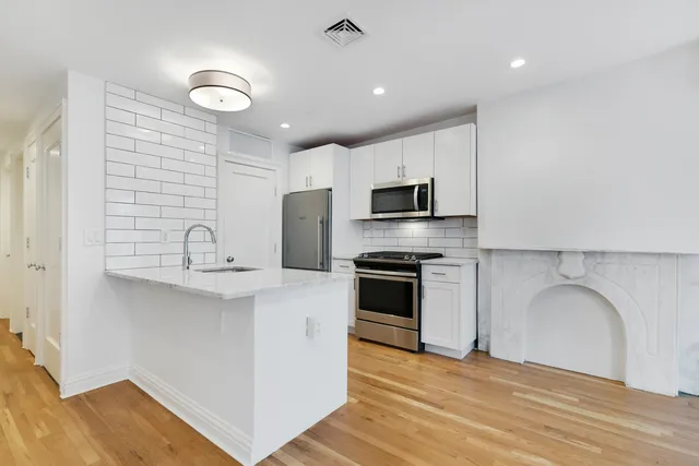 a kitchen with stainless steel appliances a sink a stove a refrigerator cabinets and a dining table