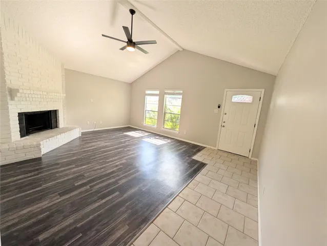 an empty room with windows and fireplace